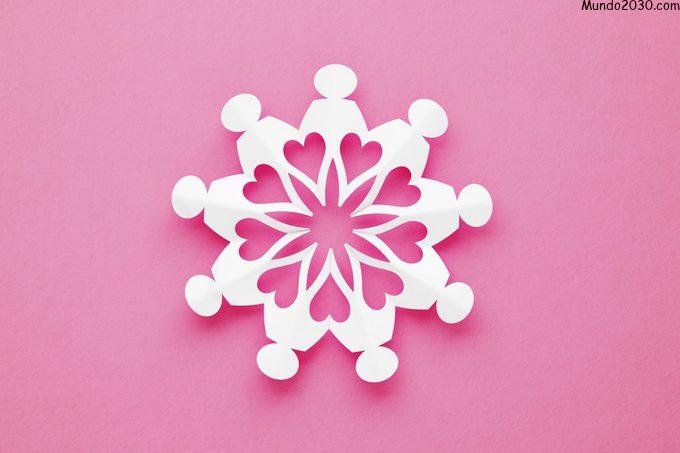 Cadena de personas voluntarias hechas de papel creando un patrón similar a un copo de nieve sobre fondo rosa
