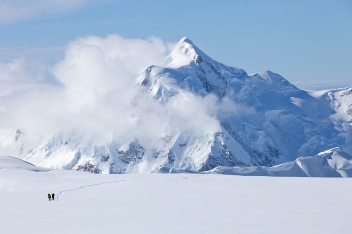 Dos montañeros están cruzando un glaciar en el monte.  Mc Kinley, Alaska.  Mount Hunter está en el fondo.