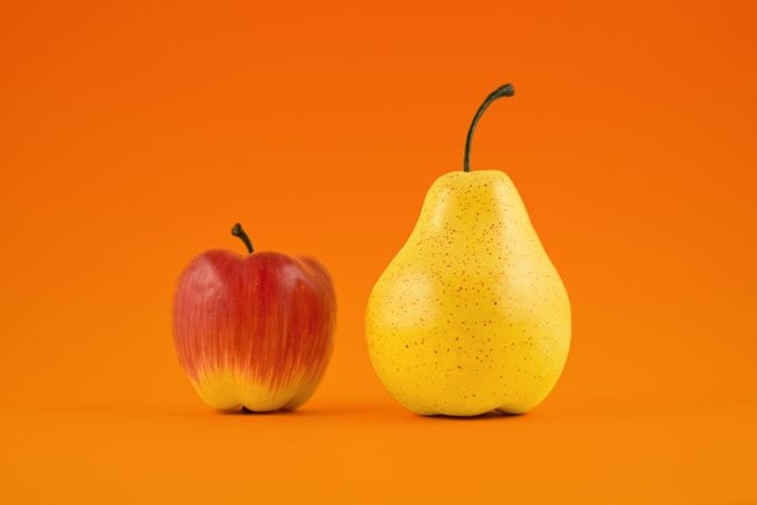 manzana roja junto a pera amarilla sobre fondo naranja