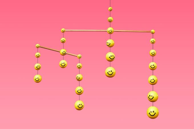 móvil compuesto por caras sonrientes amarillas sobre fondo rosa para representar a la comunidad y la red de apoyo para una vida más feliz