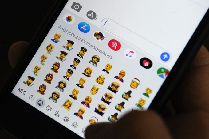 La persona que tiene un iPhone muestra emojis en el teclado en una aplicación de mensajes de texto