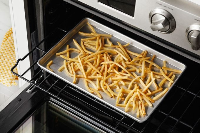 papas fritas mcdonalds esparcidas en una bandeja para hornear en un estante en un horno abierto