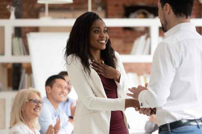 Happy proud black female employee get rewarded handshake boss